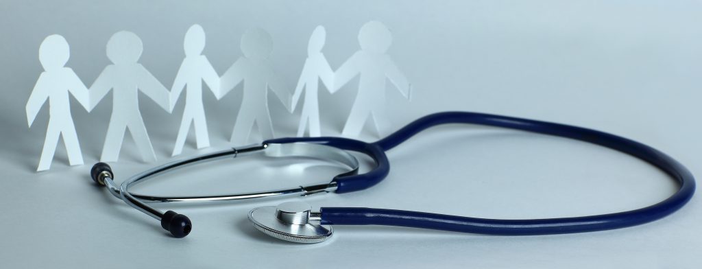 Estetoscopio sobre superficie junto a figuras humanas recortadas que simbolizan comunidad y atención en salud